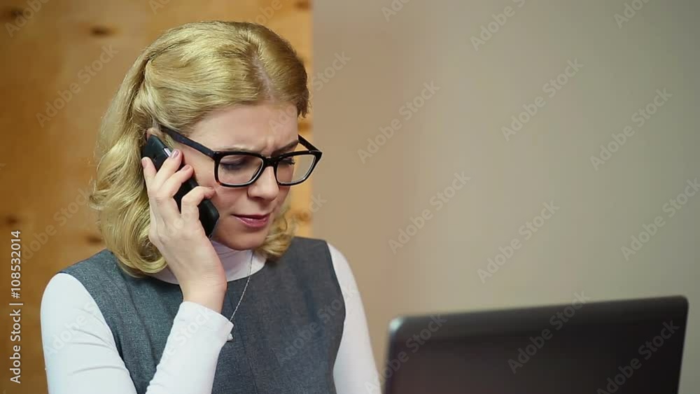 Successful businesswoman working on laptop in office, talking on the phone Successful businesswoman working on laptop in office, talking on the phone
