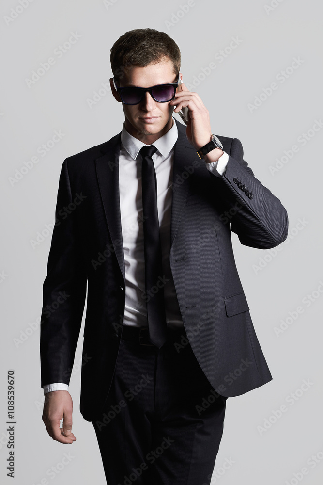 businessman speaking on the phone. handsome man in suit and sunglasses businessman speaking on the phone. handsome man in suit and sunglasses