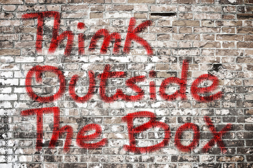 Think outside the box written on a brick wall - concept image