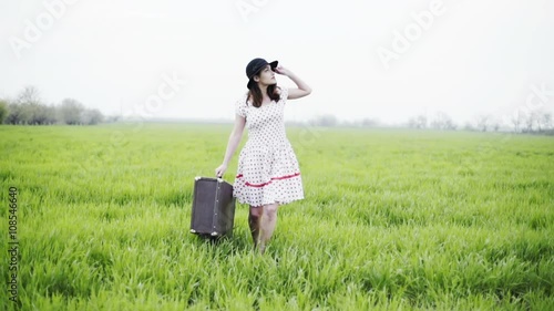 Wallpaper Mural woman dressed in retro style carries luggage through the green field slow motion  Torontodigital.ca