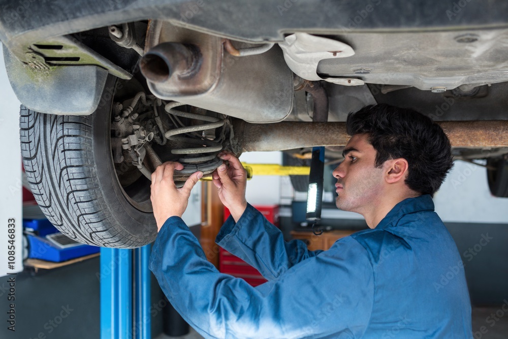 Mechanic repairing suspension of a car Mechanic repairing suspension of a car