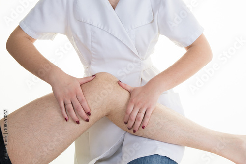 Physiotherapist doing calf massage to her patient in medical office photo