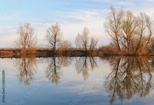 The reflection of sky and trees from the opposite bank in the river