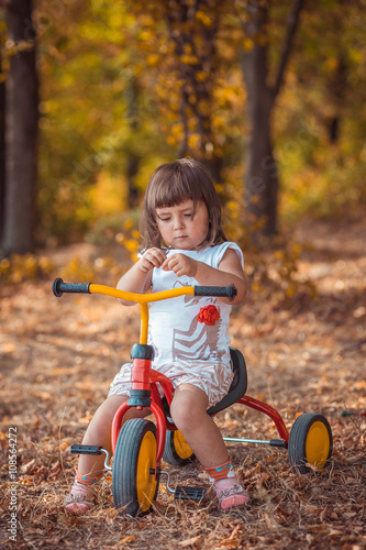 Adorable girl riding a bike on beautiful autumn day. childhood, leisure, friendship and people concept. walks in the woods on a sunny autumn day. Children playing outdoors. Happy family. series