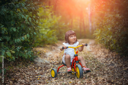 Adorable girl riding a bike on beautiful autumn day. childhood, leisure, friendship and people concept. walks in the woods on a sunny autumn day. Children playing outdoors. Happy family. series