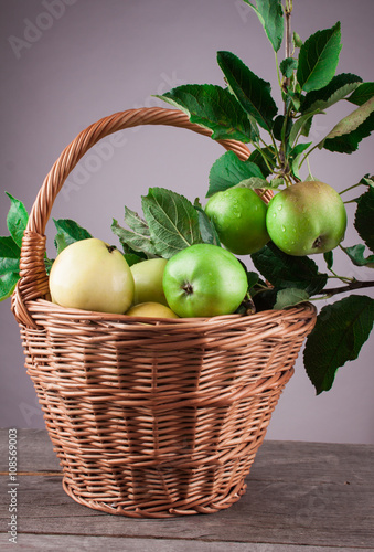 Summer apple in a wicker basket on a wooden table