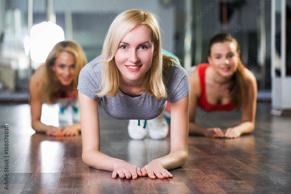 Fitness, sport, training and lifestyle concept -Group of sportive young women in the gym centre.Girls are pressed from the floor