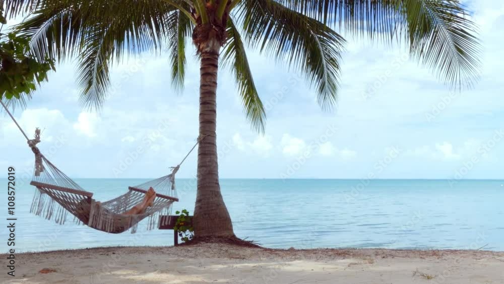 Relaxed woman lying in hammock on the beach