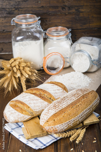 Pan de masa madre natural hecho a mano por un panadero tradicional decorado con espigas de trigo y centeno