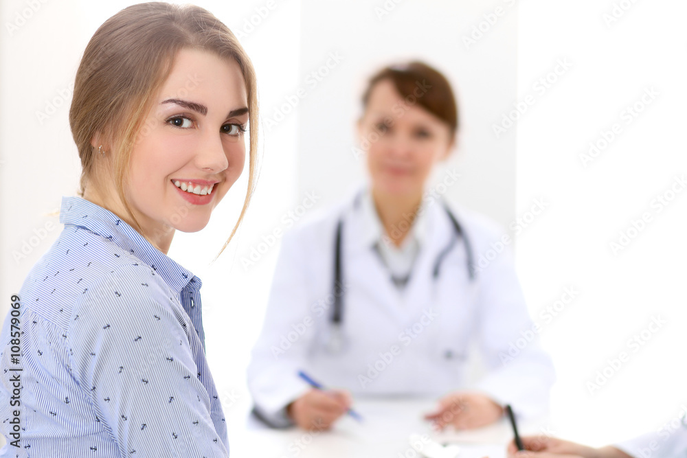 Happy smiling female patient with two cheerful doctors in the background. Medical and health care concept Happy smiling female patient with two cheerful doctors in the background. Medical and health care concept