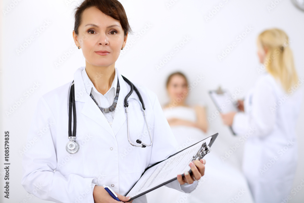 Female doctor smiling on the background with patient and his doctor Female doctor smiling on the background with patient and his doctor