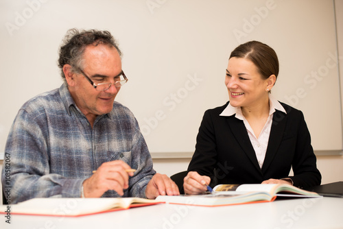 Young teacher explaining somethng to eldery man. Intergeneration photo