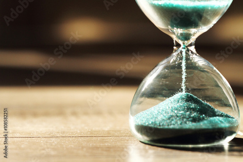 Close up hourglass on wooden background,vintage color tone