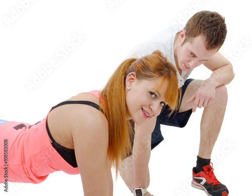 male trainer assisting young woman doing push-up