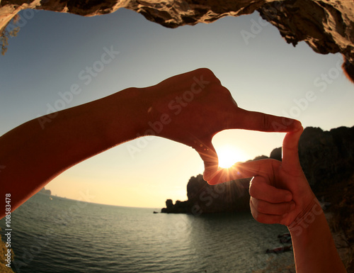 Heart shape making of hands against bright seaside sunset