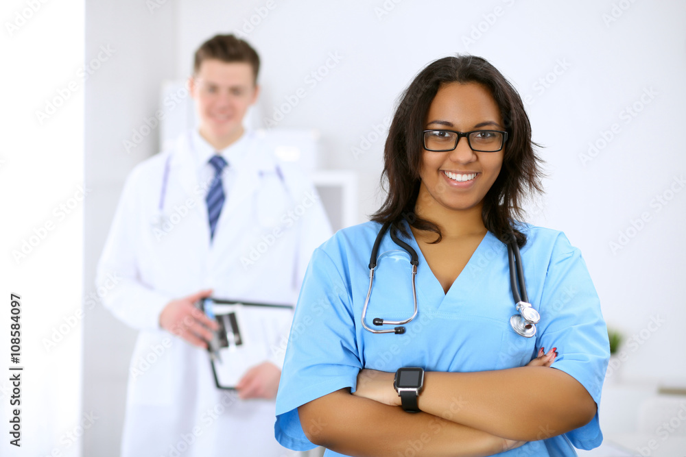 Female african american medical doctor with colleagues in background Female african american medical doctor with colleagues in background