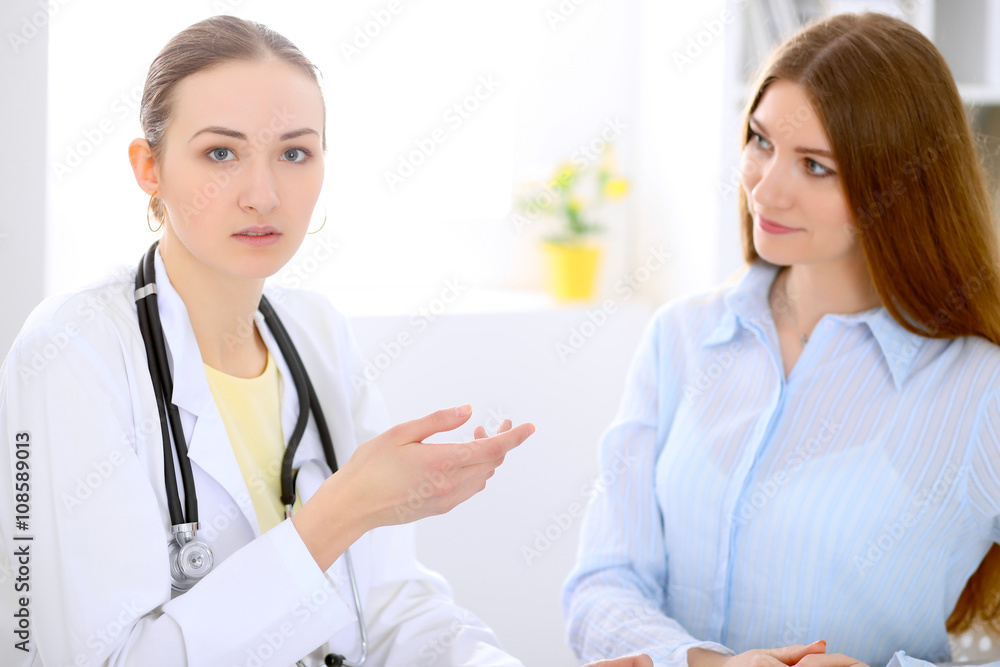 Doctor and patient sitting at the desk near window, sun shines Doctor and patient sitting at the desk near window, sun shines
