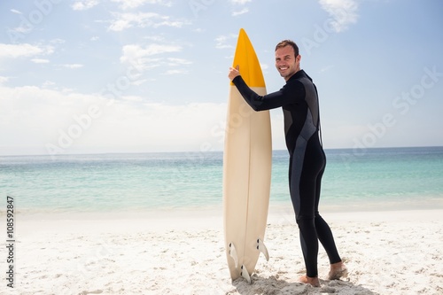 Happy surfer holding a surfboard on the beach