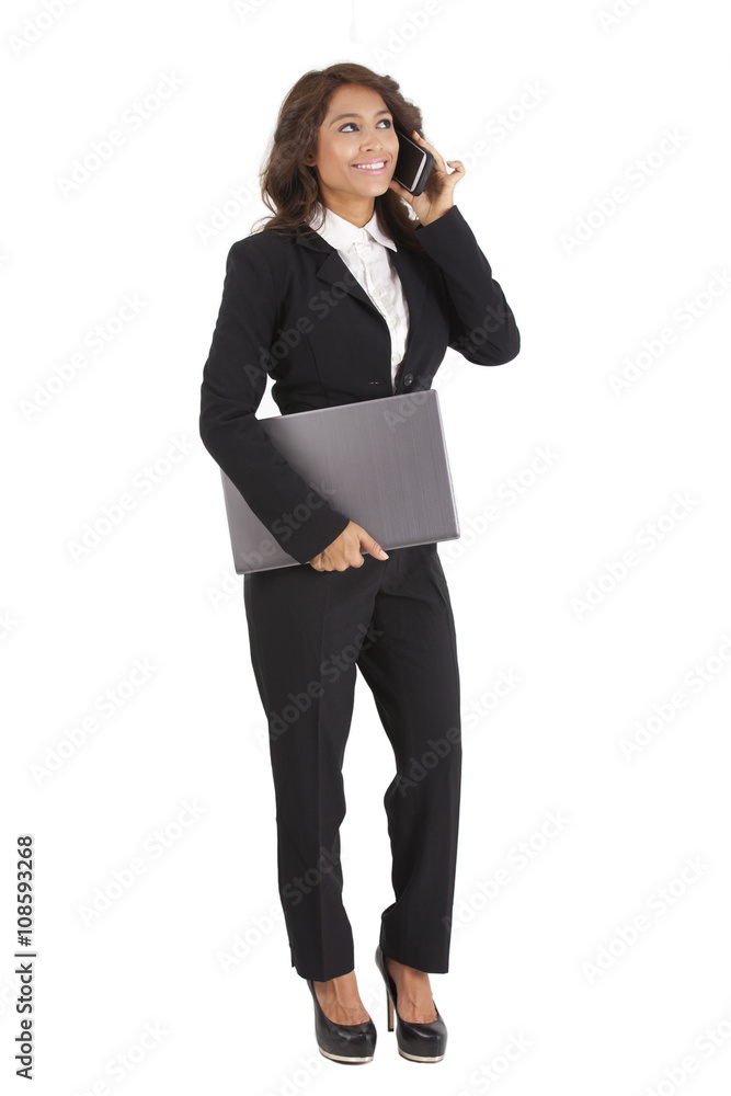Business woman using a cellphone while holding a laptop computer Business woman using a cellphone while holding a laptop computer