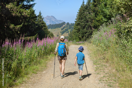 Woman and boy are walking in the French Alps in summer day
