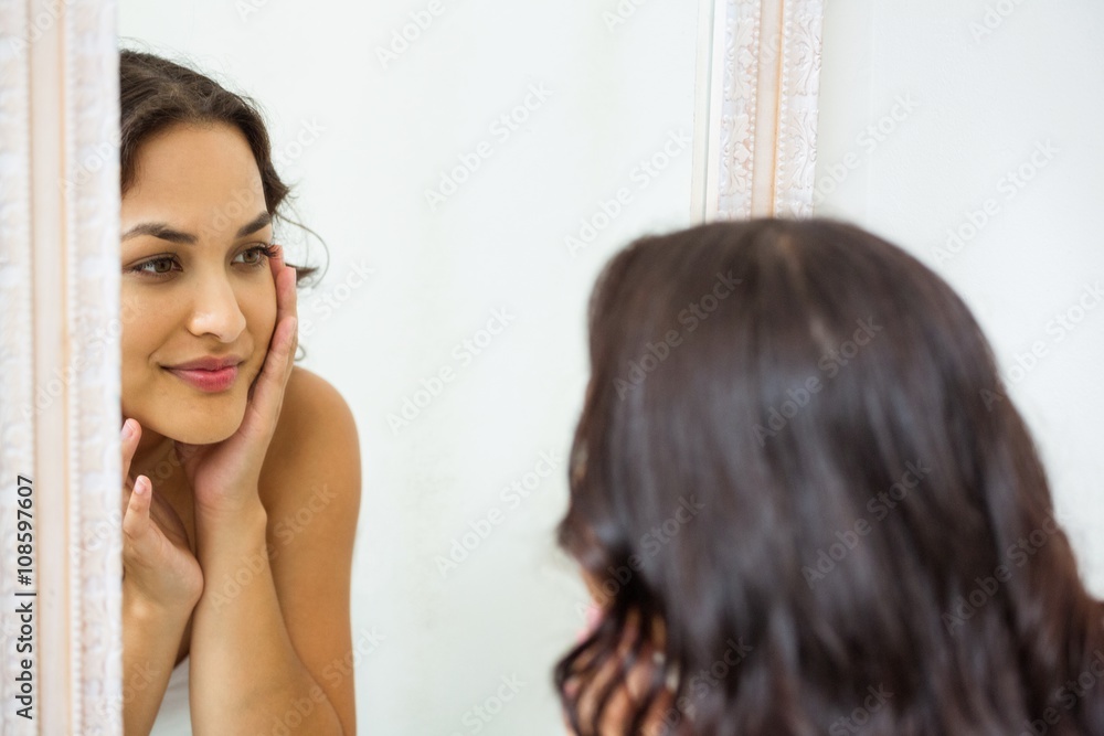 Young woman looking in mirror of bathroom Young woman looking in mirror of bathroom