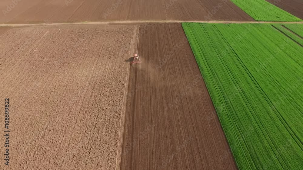 Tractor cultivating arable land for seeding crops, aerial view Tractor cultivating arable land for seeding crops, aerial view