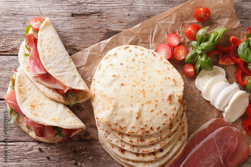 Italian street food: piadina with ham, cheese and vegetables close-up. horizontal top view
 photo