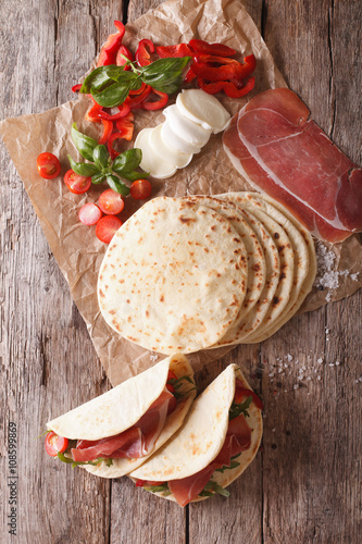Italian piadina with ham, cheese and vegetables closeup. vertical top view
