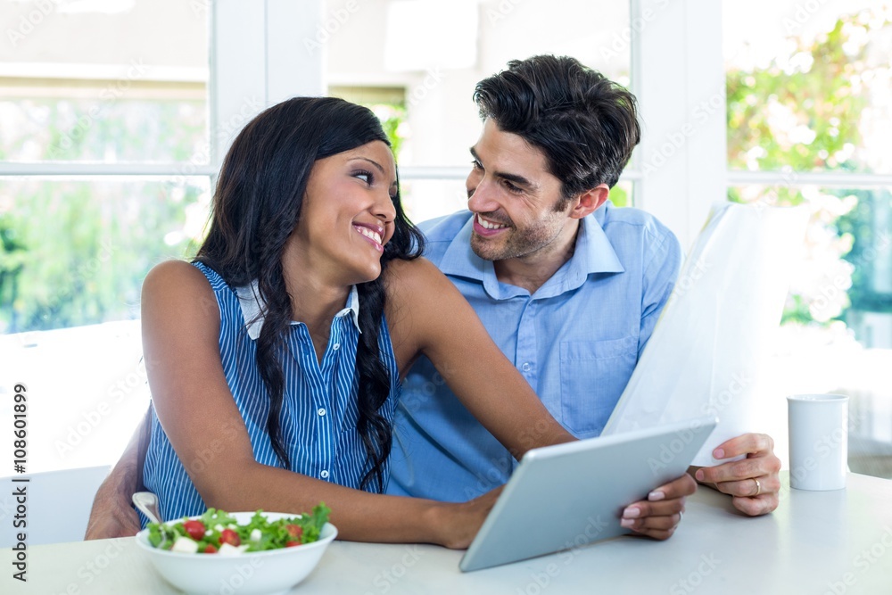 Young couple embracing while using digital tablet