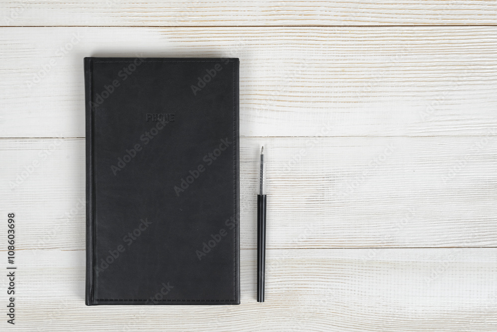 Flat lay of black notebook and pen on light wooden surface Flat lay of black notebook and pen on light wooden surface