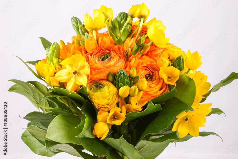 Bouquet yellow ranunkulyus with green leaves on bright background 