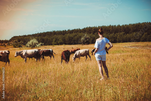  young woman in a field surrounded by cows