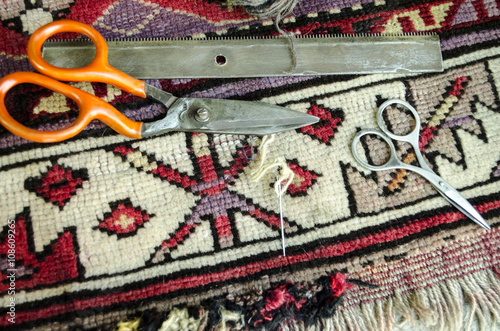 Worn old woolen carpet with scissors,a comb with needle and thread