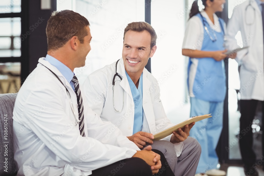 Two doctors with clipboard and discussing Two doctors with clipboard and discussing
