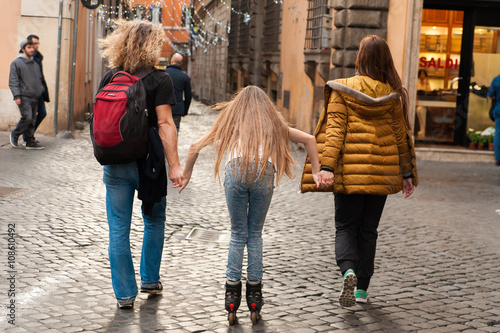 child on rolleblades helped by parents in the streets of city photo