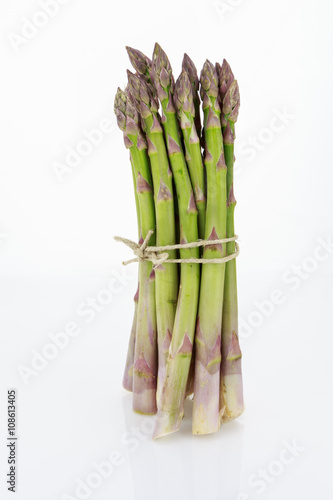 Bunch of asparagus tied with raffia cord, isolated on white background.