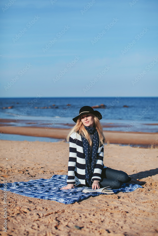 girl reading a book sitting on the beach