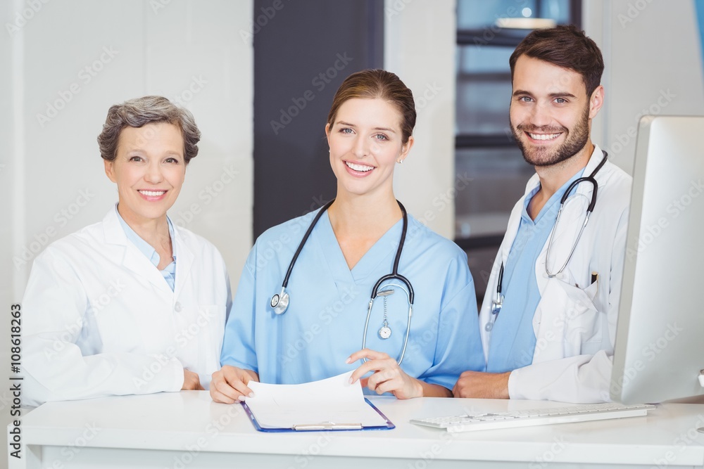 Portrait of smiling doctor team standing at computer desk Portrait of smiling doctor team standing at computer desk