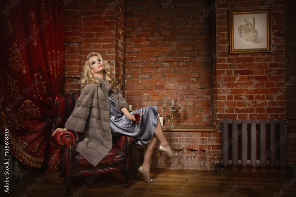 Elegant fashionable woman wearing fur cape in a vintage interior