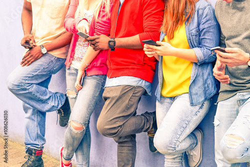 Multiracial group of friends texting sms and looking down to cell phone - Interracial students hands using mobile - Concept of young people addiction to web technology - Focus on hand of red hair girl