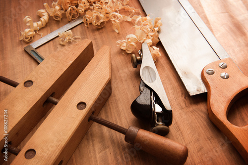 Wood working desk near the window with incandescent lighting, Wood working tools and wood shavings. photo