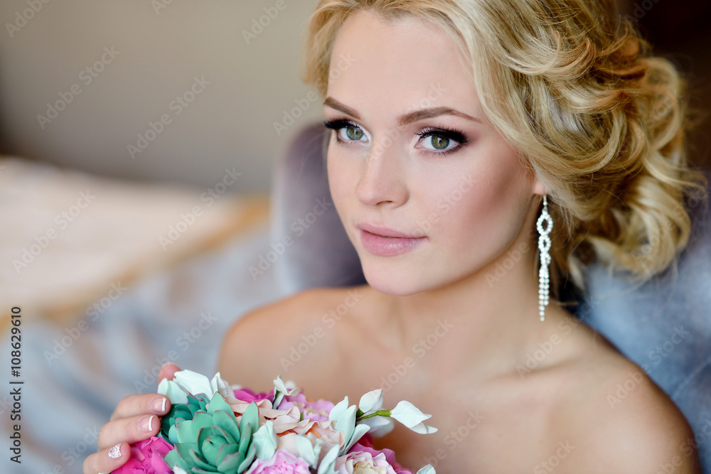 Beauty bride in bridal gown with bouquet and lace veil indoors. Beautiful model girl in a white wedding dress. Female portrait of cute lady. Woman with hairstyle