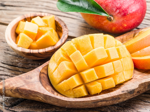 Obraz na płótnie Mango fruit and mango cubes on the wooden table.
