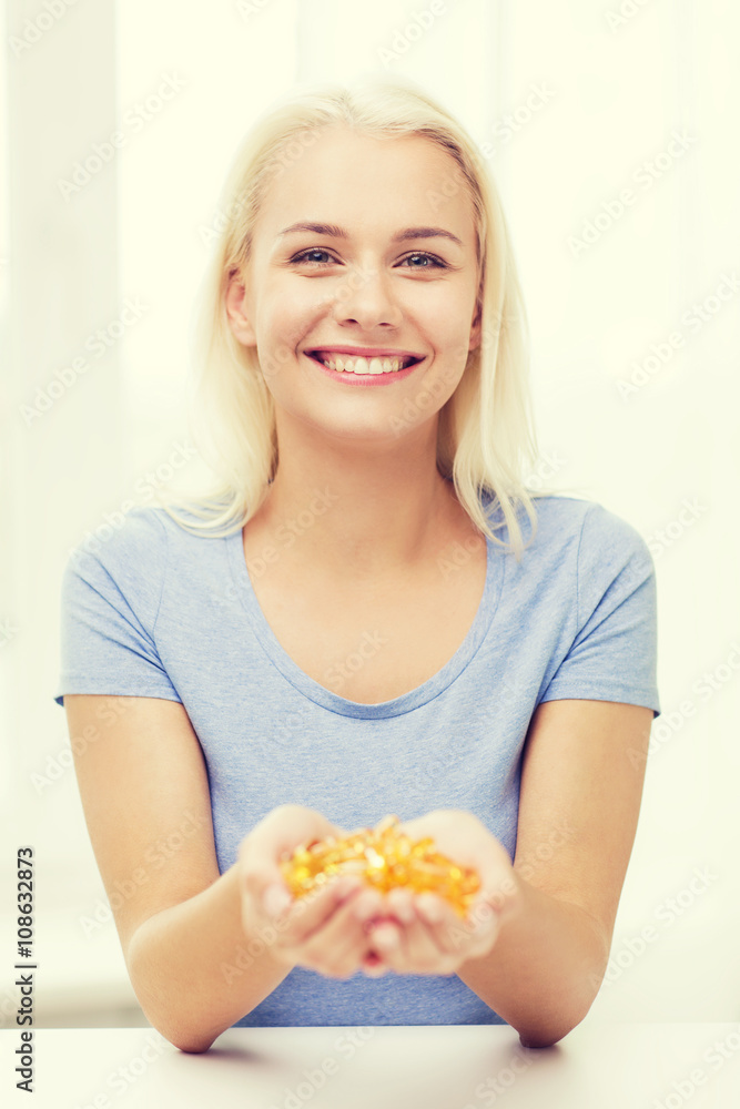 happy woman holding fish oil capsules at home happy woman holding fish oil capsules at home