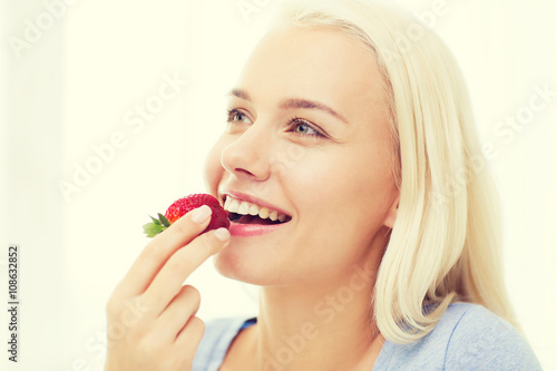 happy woman eating strawberry at home