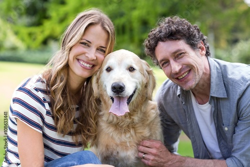 Smiling couple with dog in the park