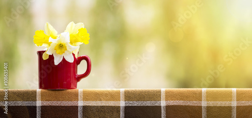 Fototapeta Naklejka Na Ścianę i Meble -  Easter flowers in a red cup - website banner with copy space