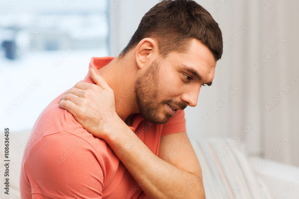 unhappy man suffering from neck pain at home unhappy man suffering from neck pain at home