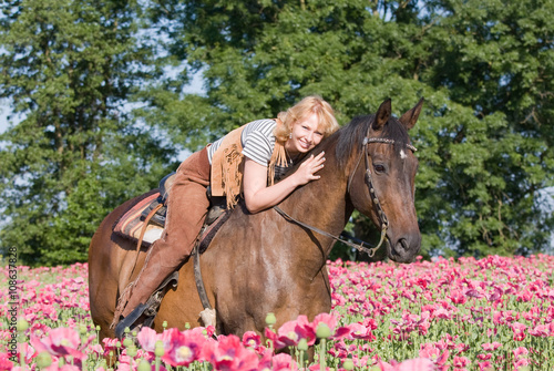 Attractive woman posing on horse in the poppy field