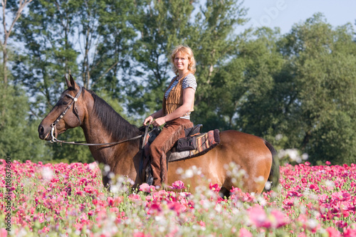 Attractive woman posing on horse in the poppy field © lenkadan